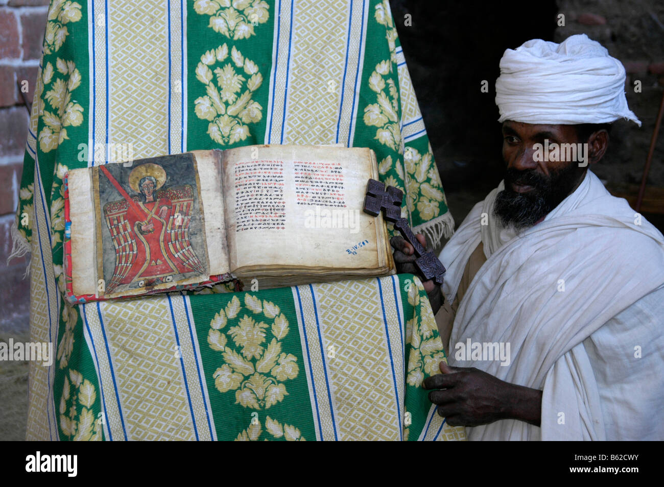 Äthiopischen orthodoxen Priester halten alte Bibel mit einem bunten Bild eines Heiligen, monolithische Kirche, Lalibela, Äthiopien, Afrika Stockfoto