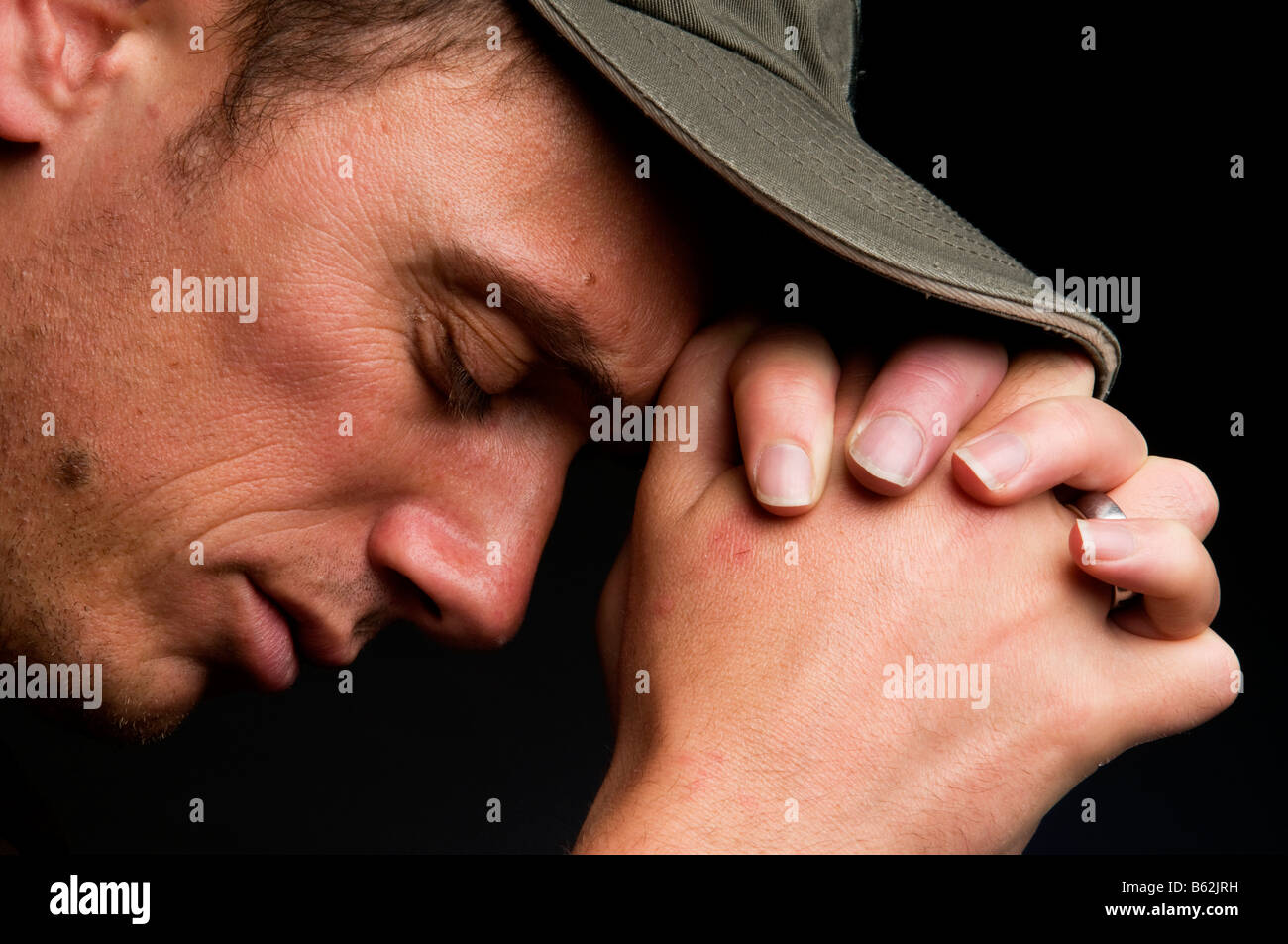 Junger Mann, der betet auf schwarzem Hintergrund Stockfoto
