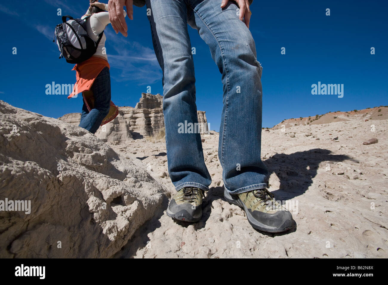 Niedrige Schnittansicht eines Mannes auf erodierten Felsen stehend, mit einer Frau, die im Hintergrund laufen Stockfoto