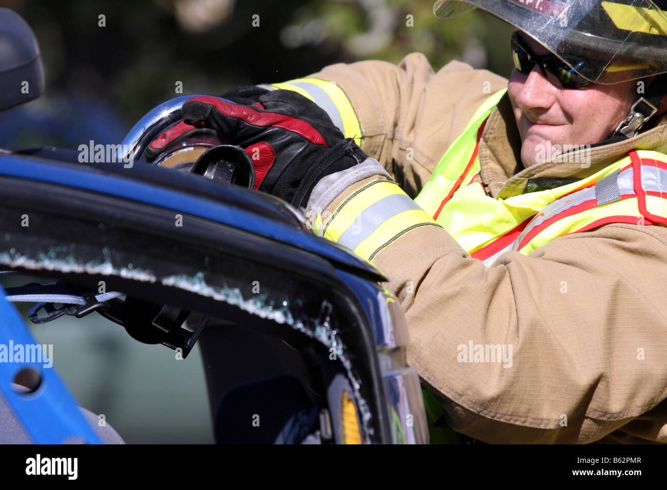 Ein Feuerwehrmann hat das Backen des Lebens Bergung Werkzeug benutzt, um durch eine Stütze eines Autos zu schneiden, die über gerollt hat Stockfoto
