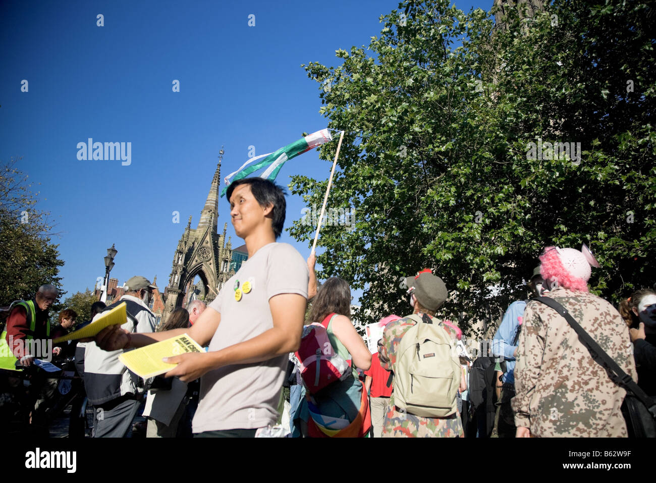 Young Oriental Mannhände Flugblätter in Frieden März. Albert Square, Manchester, UK. Stockfoto