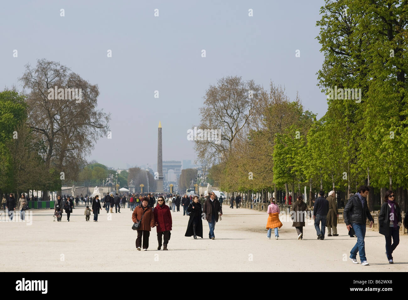 Besucher des Jardin des Tuileries in Paris schlendern zusammen mit dem Place De La Concorde und den Arc de Triomphe dahinter Stockfoto