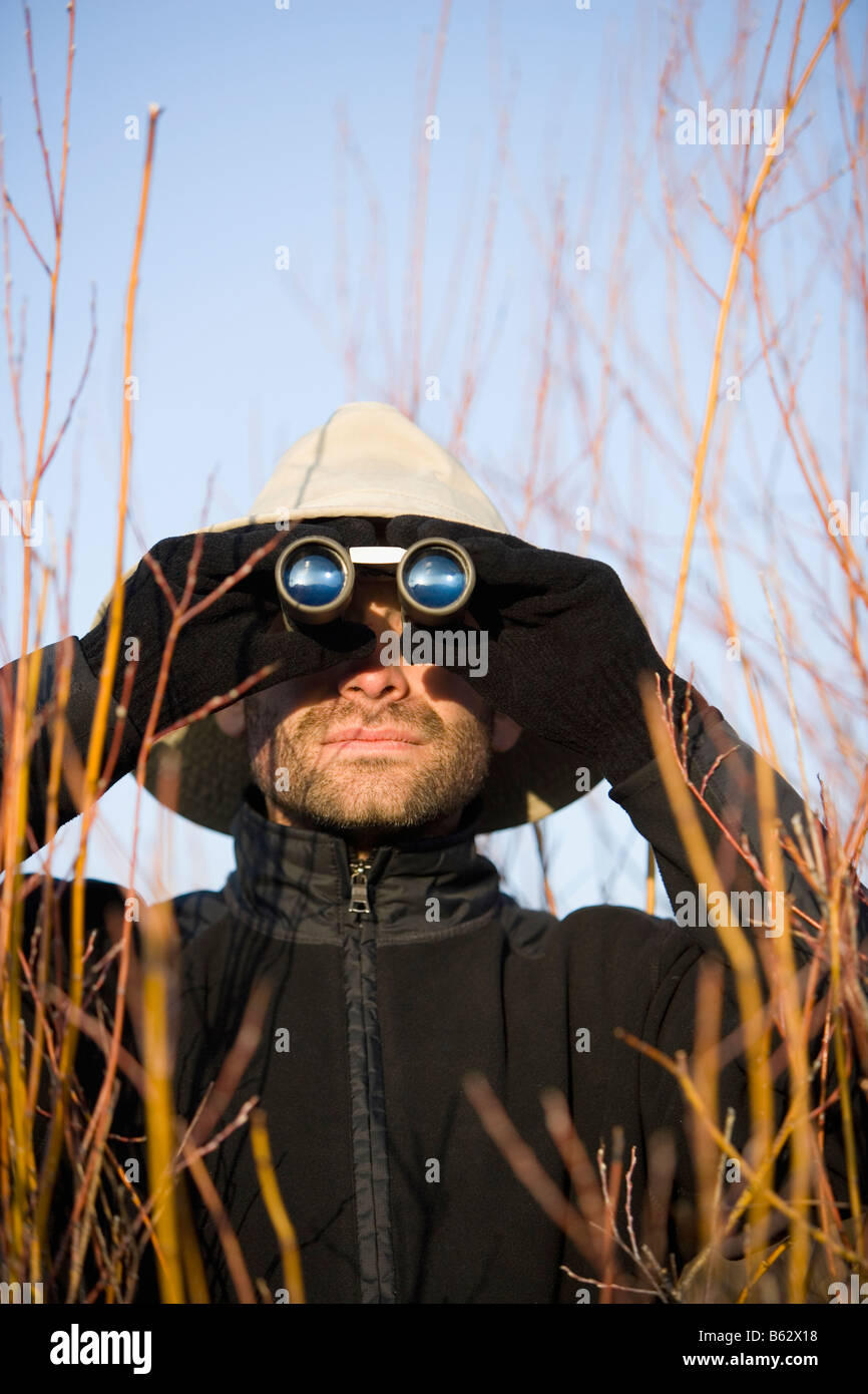 Mitte erwachsenen Mannes Blick durch ein Fernglas in einem Wald Stockfoto