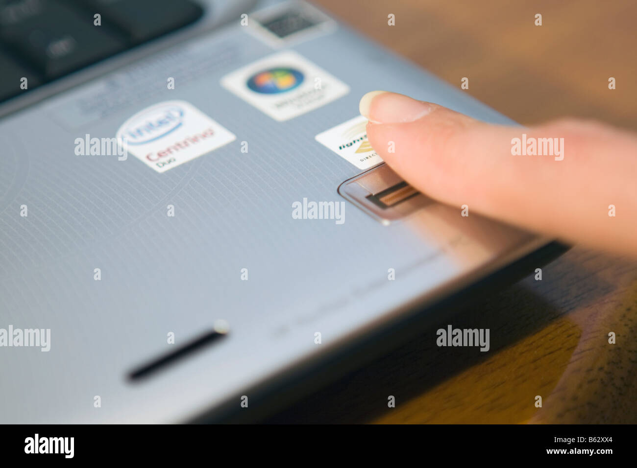 Anmelden an einem Notebook-PC durch Streichen sie Frau finger über einen biometrischen Fingerabdruckleser. Stockfoto