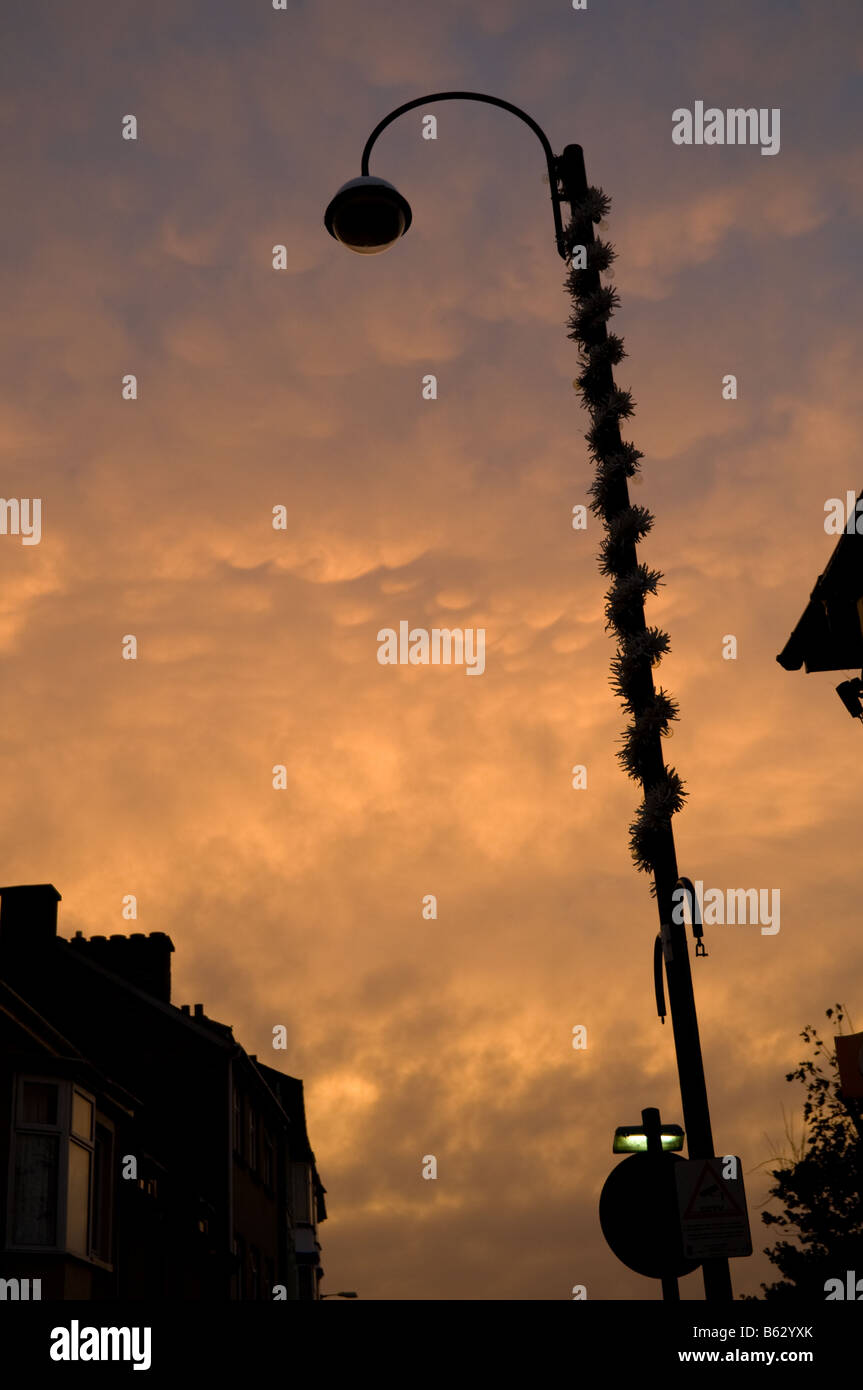 leuchtende Licht auf Belichtungsverhältnisse Mammatus Wolken bei Sonnenuntergang, launisch drückend unheimliche Gefühl, Laternenpfahl in der Silhouette, UK Stockfoto