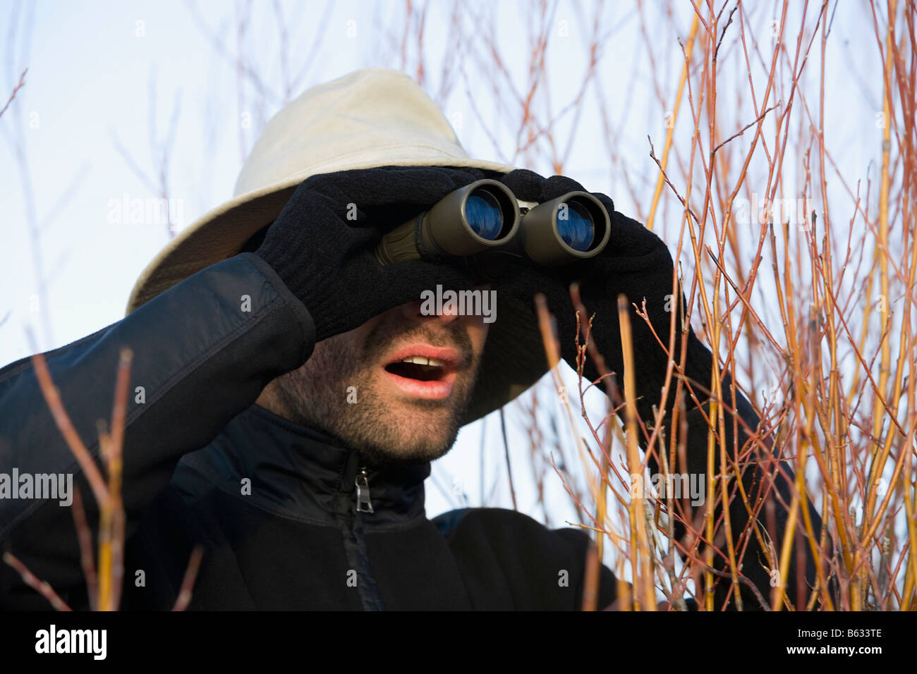Mitte erwachsenen Mannes Blick durch ein Fernglas in einem Wald Stockfoto