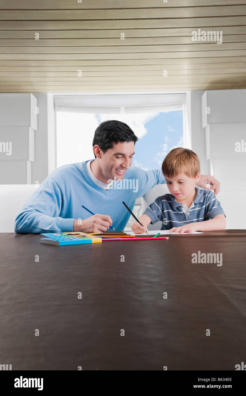 Mitte erwachsenen Mannes behilflich sein Sohn in seine Hausaufgaben Stockfoto