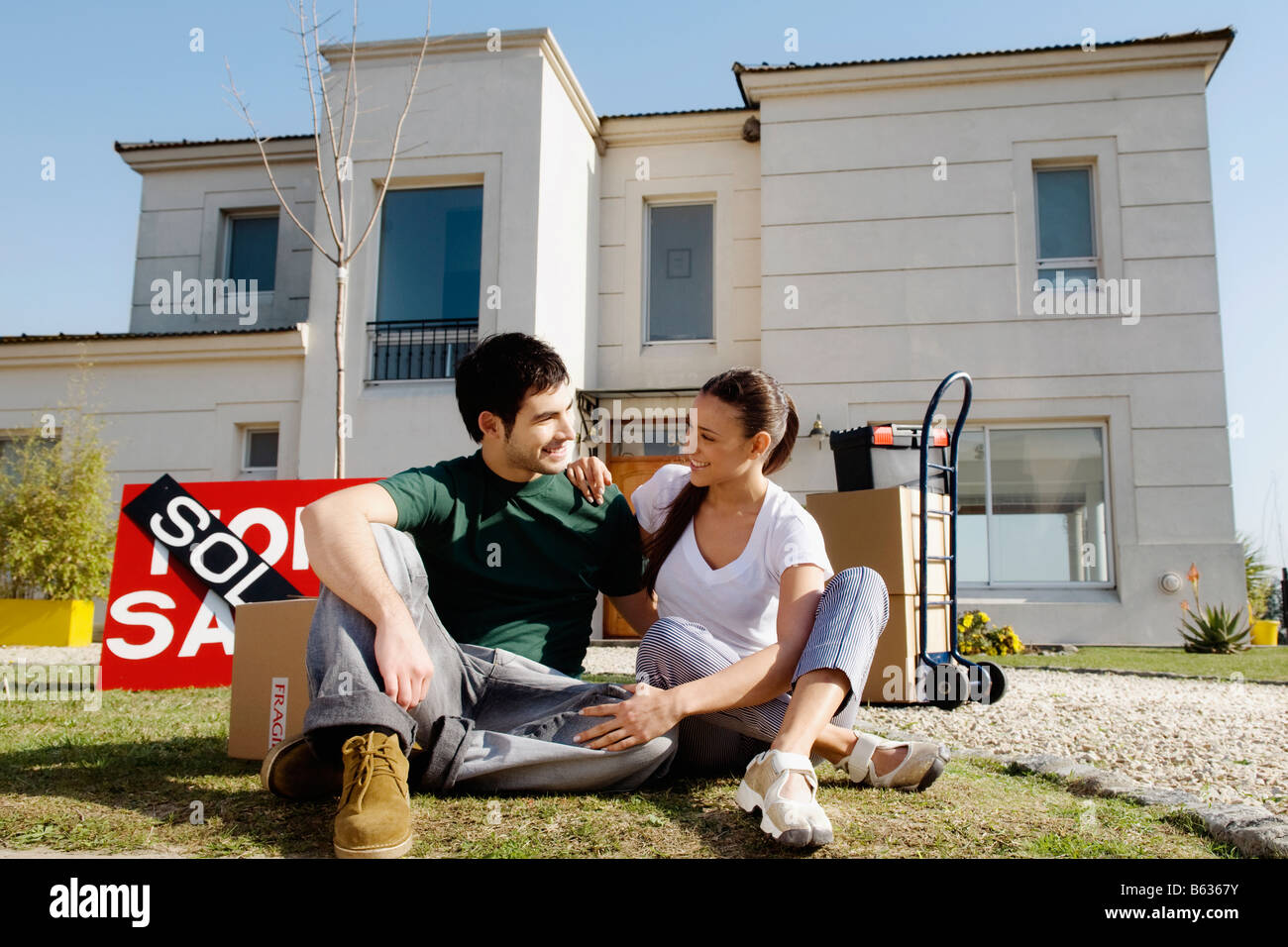 Junges Paar sitzt vor einem verkauften Informationstafel Stockfoto