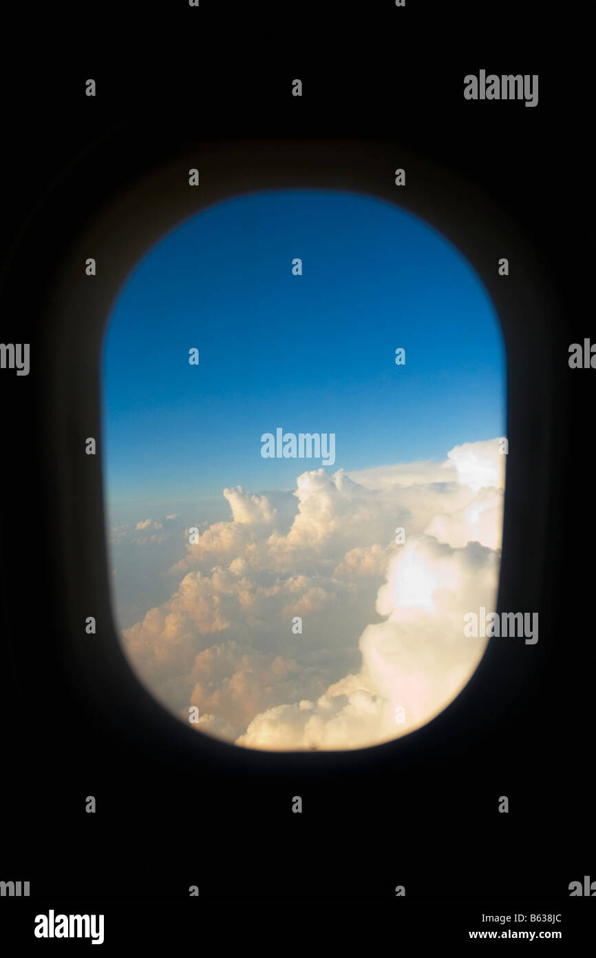 Wolken, die durch ein Fenster eines Flugzeugs betrachtet Stockfoto