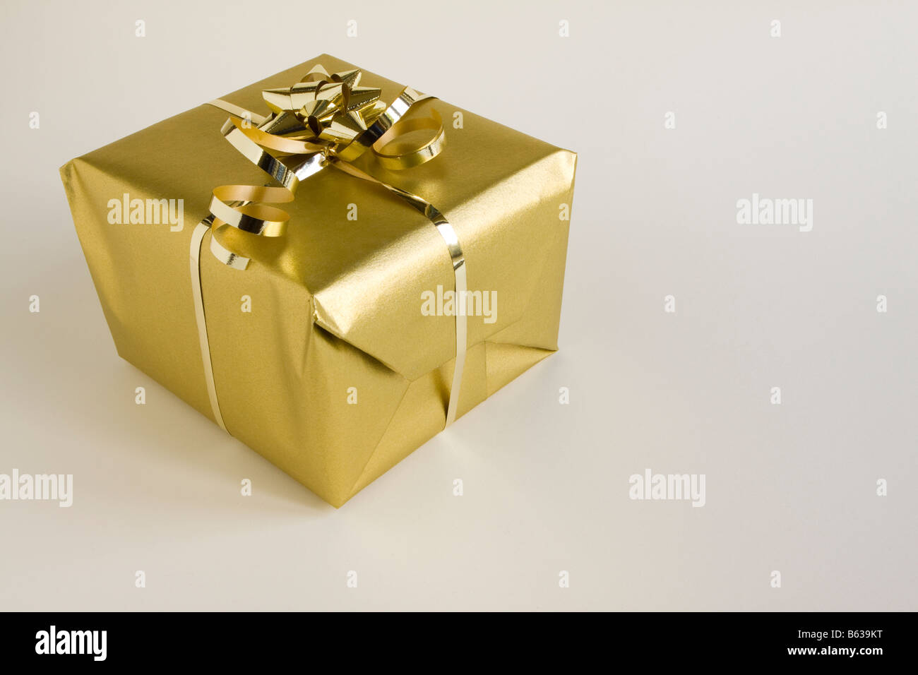 Ein Geschenkpaket verpackt in Goldpapier mit Schleife Stockfoto