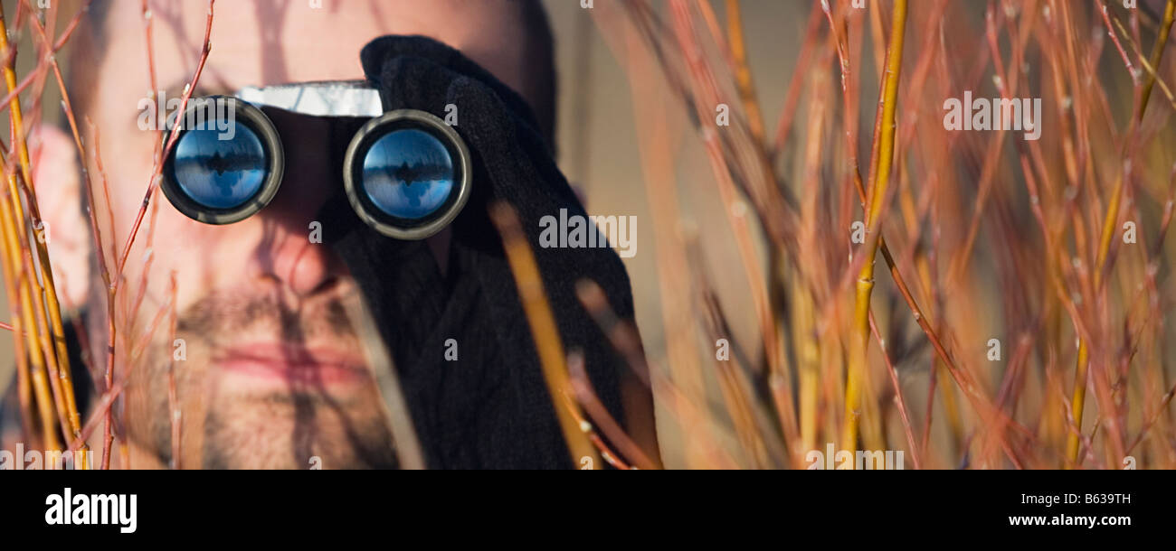 Mitte erwachsenen Mannes Blick durch ein Fernglas in einem Wald Stockfoto