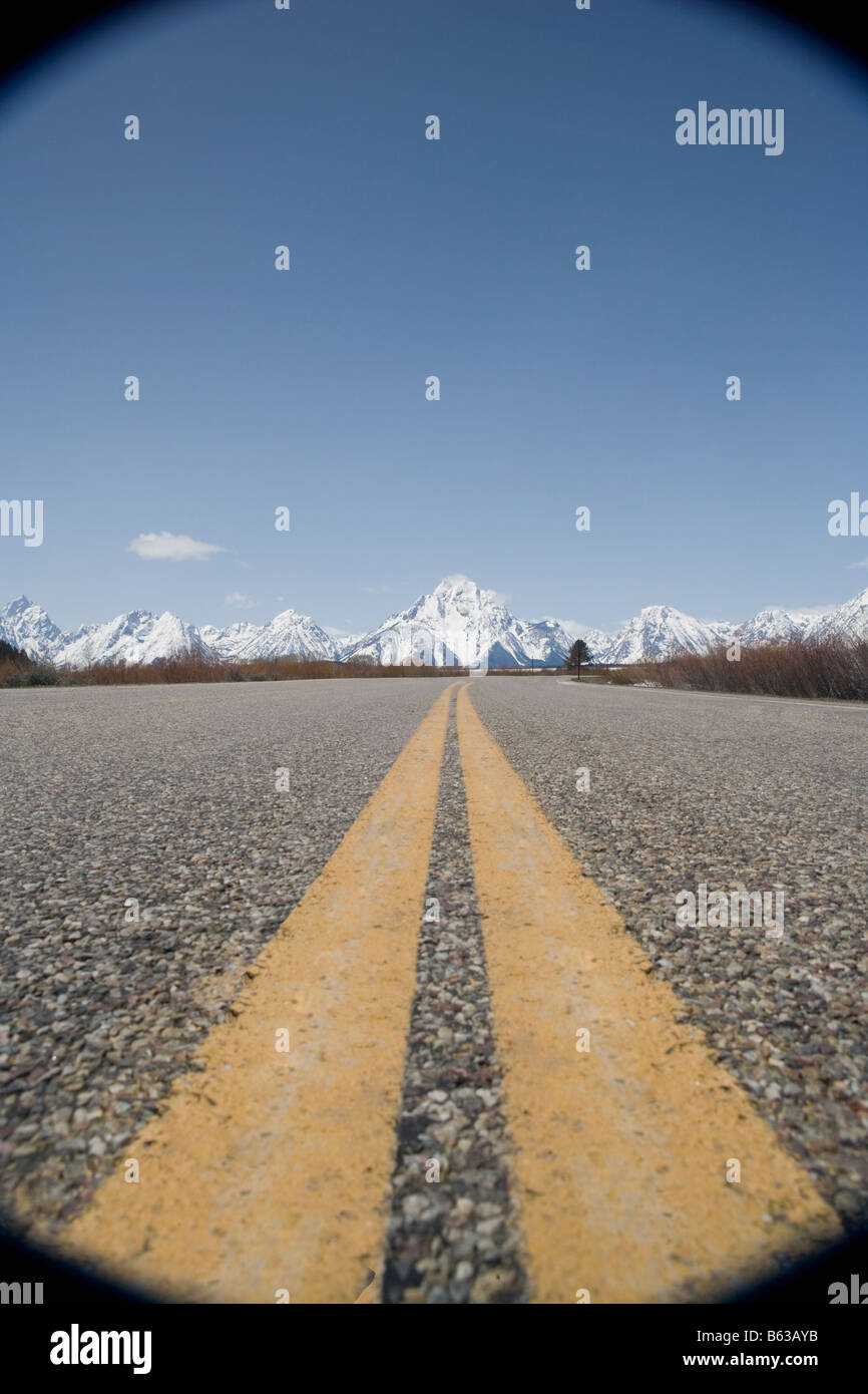 Trennlinien auf einer Straße mit Bergen im Hintergrund, Grand-Teton-Nationalpark, Wyoming, USA Stockfoto