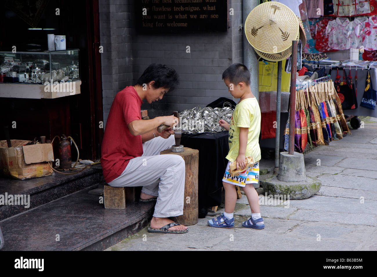 Chinesischer Mann und junge, die Herstellung von Schmuck vor seinem Strassenlokal, Yangshuo, China Stockfoto