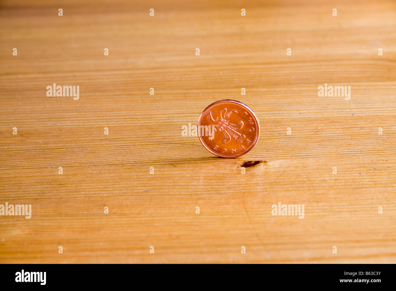 Eine UK-zwei Pence-Münze vertikal auf einer Kiefer-Tabelle Stockfoto