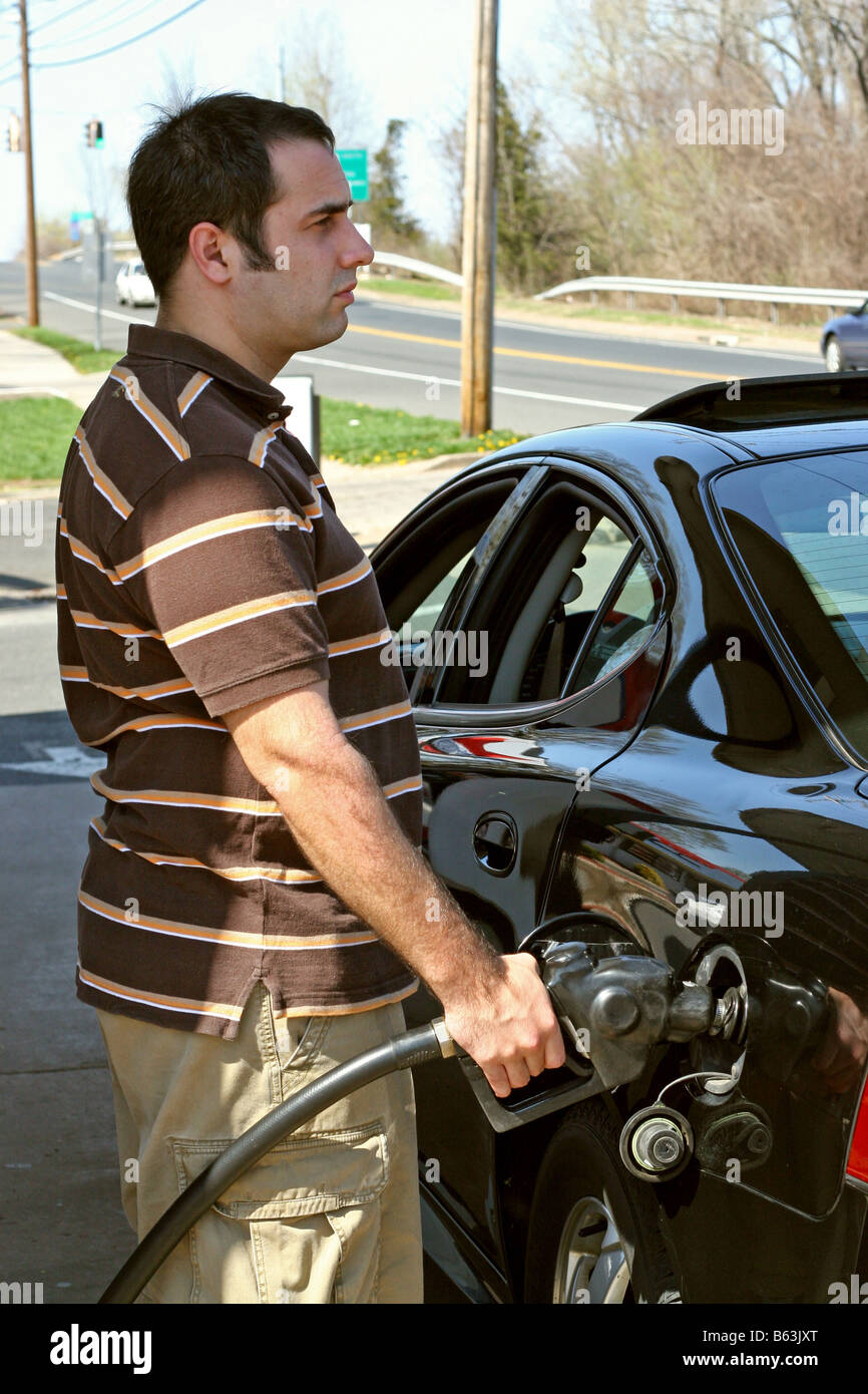 Ein Mann, hohen Preisen Gas in seinem Auto mit einem angewidert Ausdruck auf seinem Gesicht Pumpen Stockfoto
