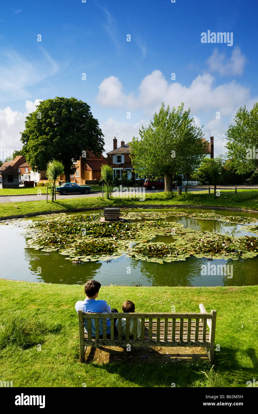 Ententeich, UK - zwei Kinder beobachten die Enten in Wisborough Green Village, West Sussex, England Stockfoto