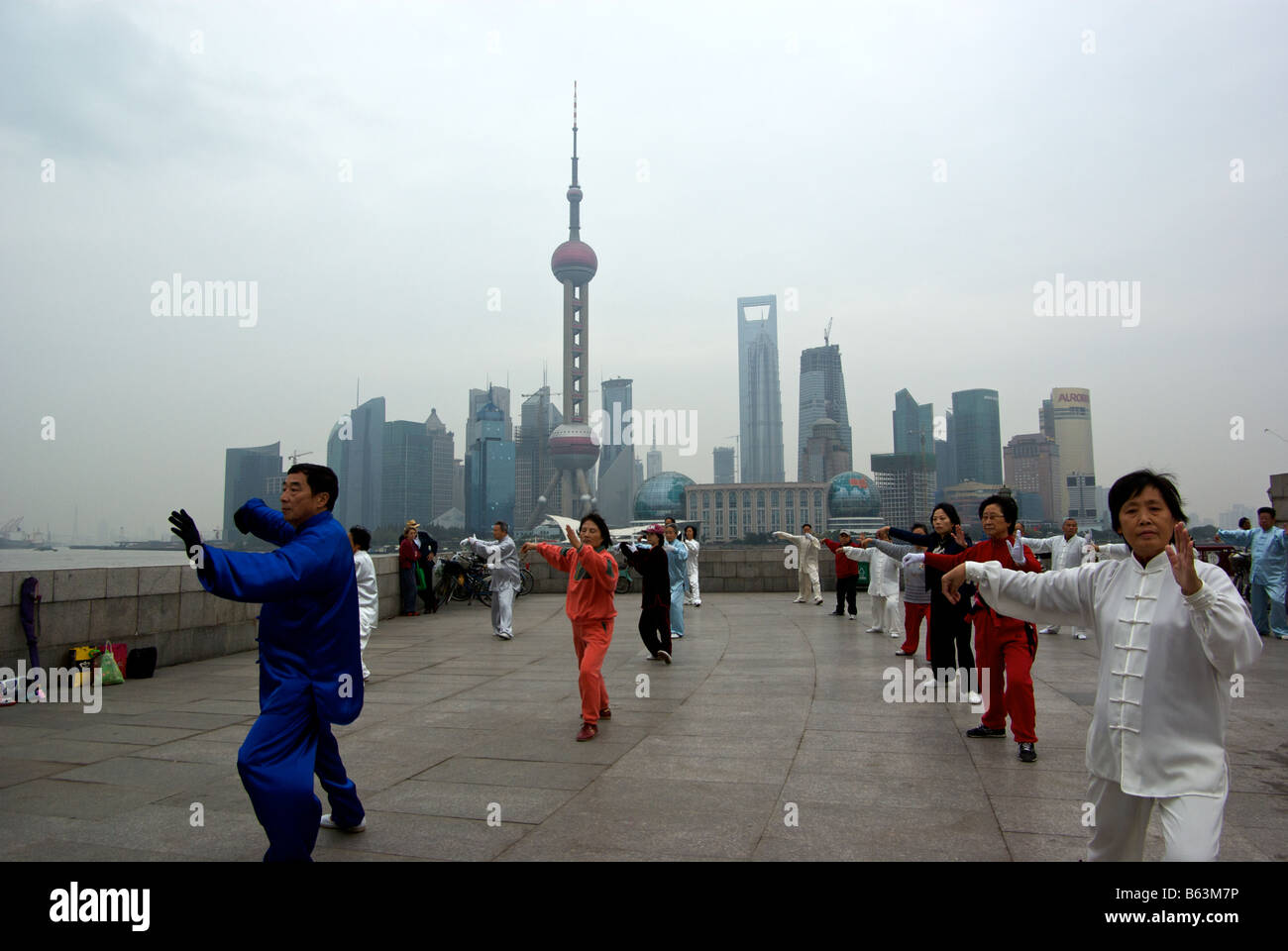 Praktizierende des Tai Chi üben sie ihre rituellen Kampfkünste am Bund feuchten frühmorgens Stockfoto