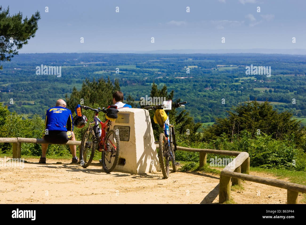 Zwei Radfahrer genießen die Aussicht über die Weald und South Downs Landschaft an der Spitze der Leith Hill, Surrey, England UK Stockfoto