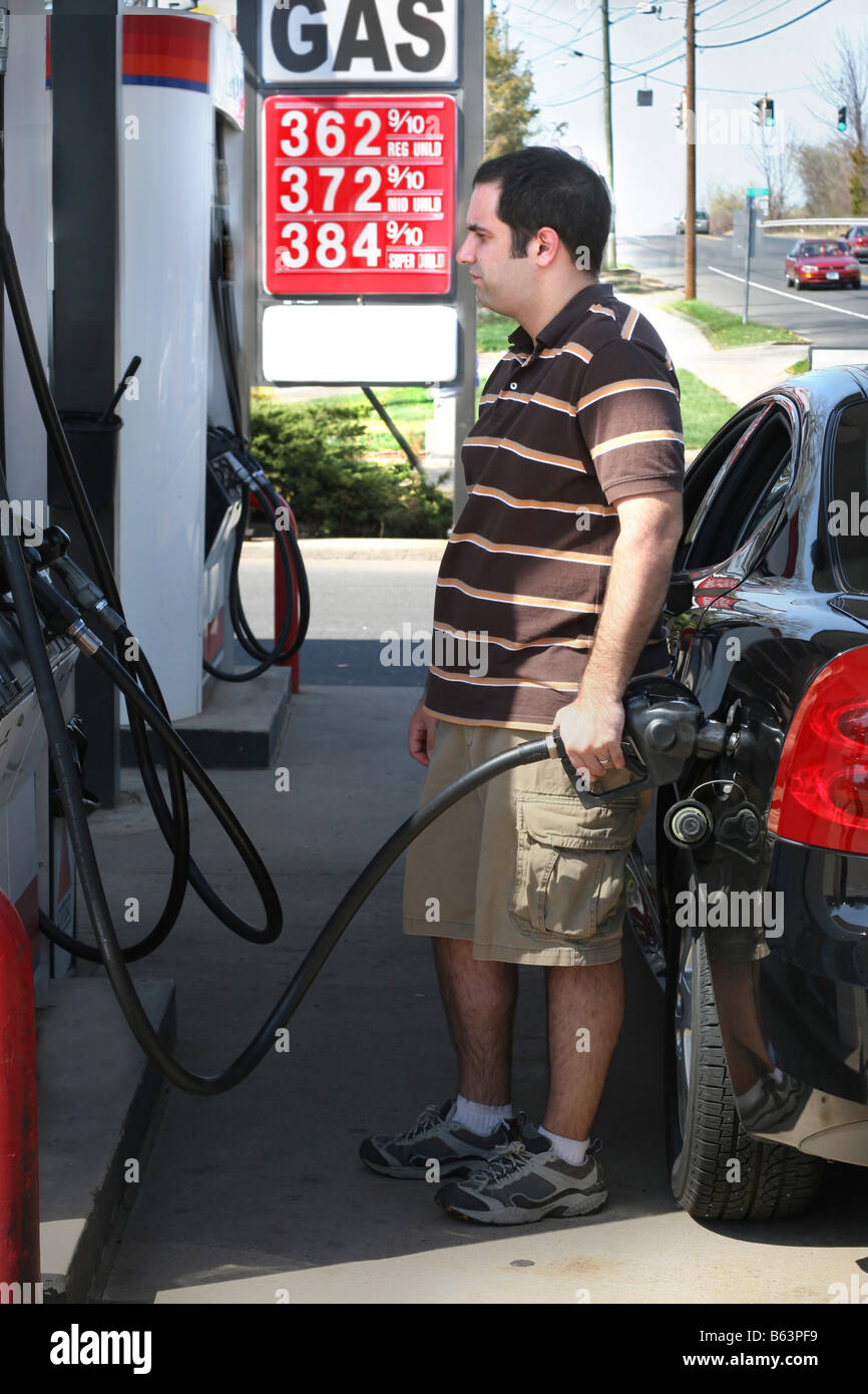 Ein Mann, hohen Preisen Gas in seinem Auto mit einem angewidert Ausdruck auf seinem Gesicht Pumpen Stockfoto