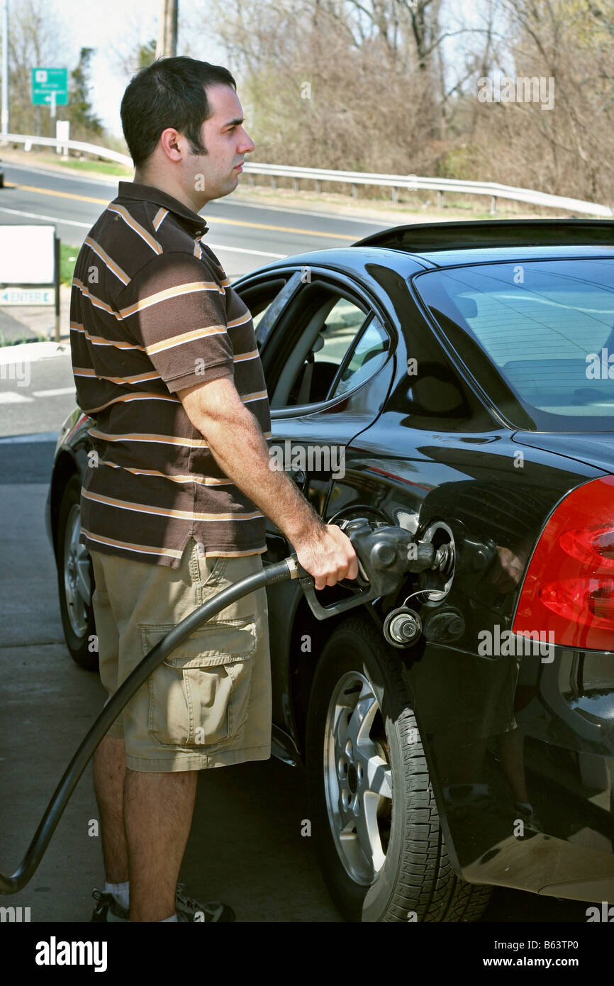 Ein Mann, hohen Preisen Gas in seinem Auto mit einem angewidert Ausdruck auf seinem Gesicht Pumpen Stockfoto