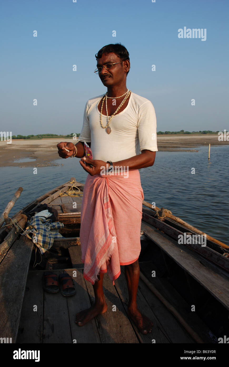 Bootsmann in seinem Boot stehend, Rollen eine Zigarette. Varanasi, Indien. Stockfoto