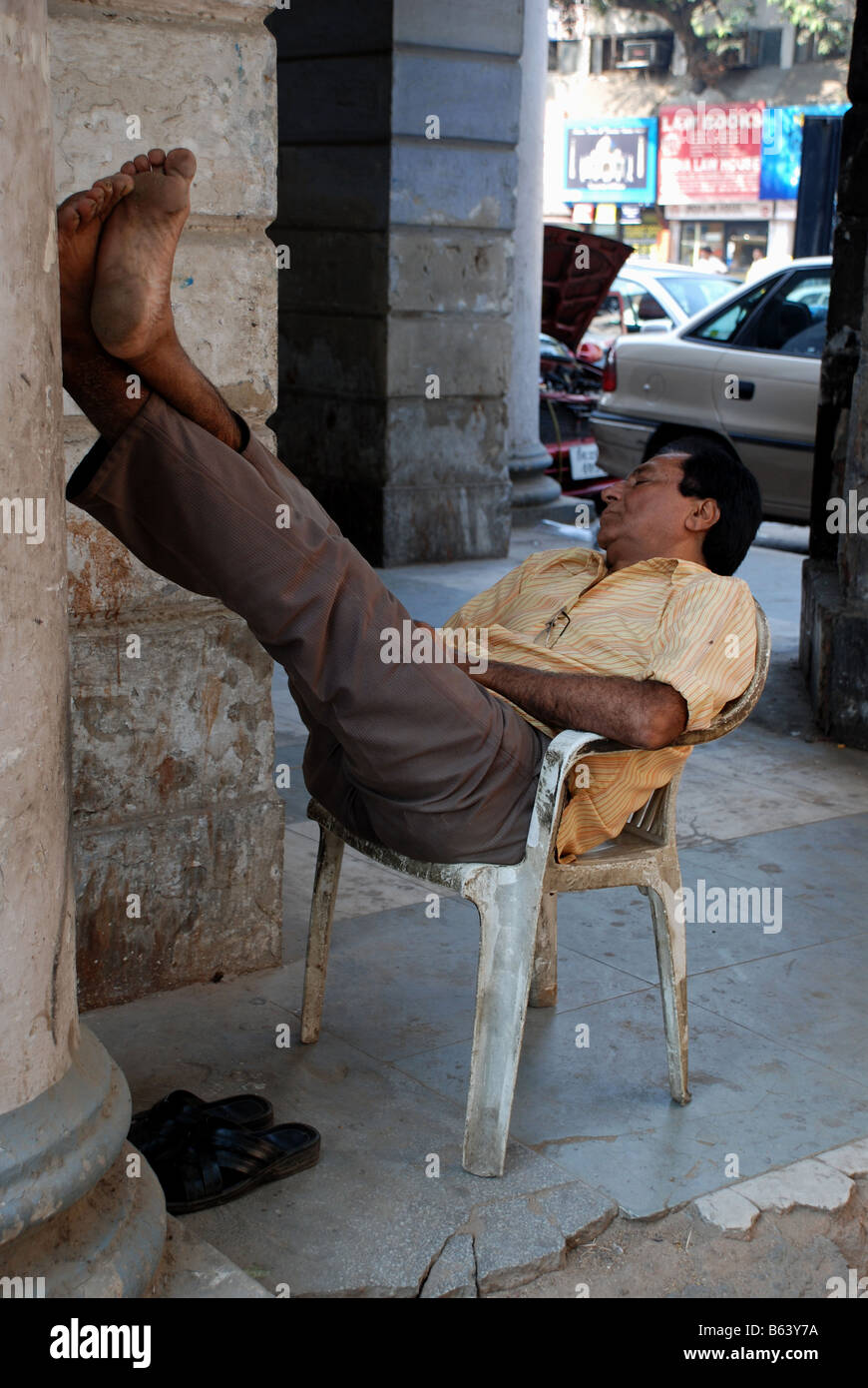 Mann oben auf Wand mit Füßen auf der Straße schlafen. Delhi, Indien. Stockfoto