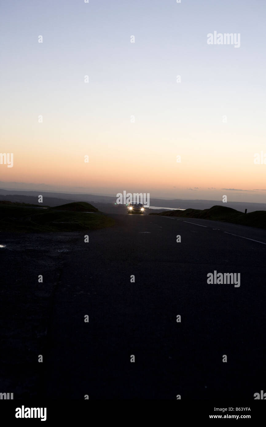 Auto auf der Straße bei Nacht. Dartmoor Nationalpark Sonnenuntergang Winter, Devon, England, UK Stockfoto