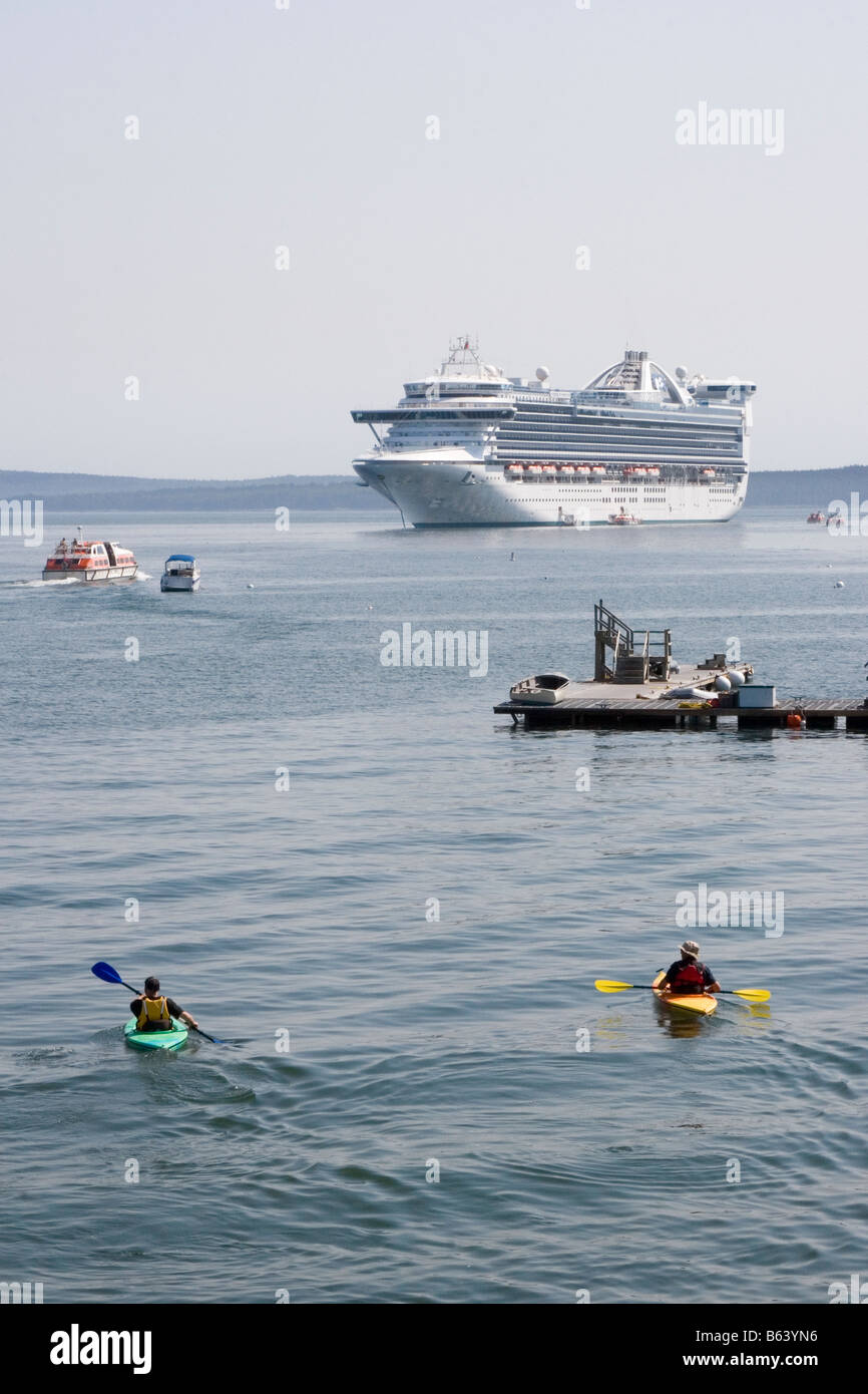 Kreuzfahrtschiff in der Nähe von Bar Harbor, Maine verankert. Touristen sind auf das Schiff in kleinen Shuttle Boote als zwei kajakfahrer Ansehen gebracht. Stockfoto