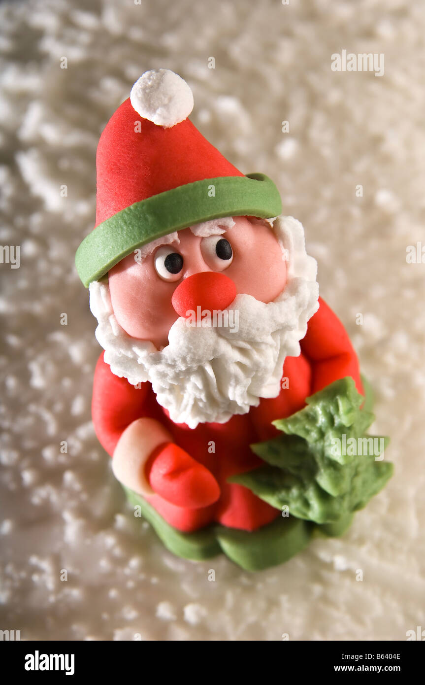 Marzipan-Weihnachtsmann saß auf vereisten Weihnachtskuchen. Er hat einen süßen Ausdruck und ängstlich blickenden Augen, die auf der Suche nach links sein. Stockfoto