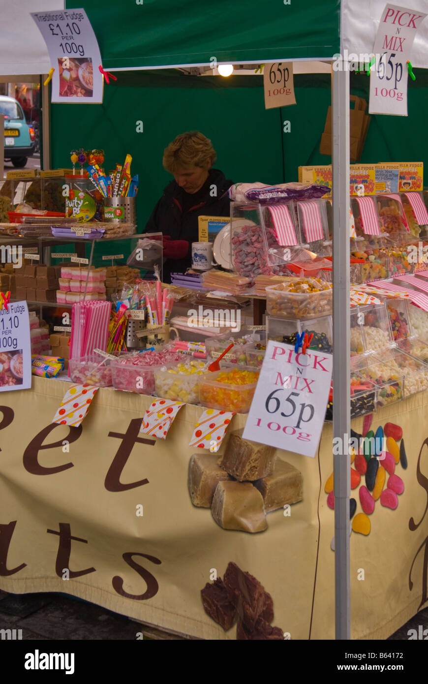 Frau, die Arbeiten an einer Pick-n mix Süßwarenladen Market Stall Shop außerhalb Verkauf von Süßigkeiten im Vereinigten Königreich Stockfoto