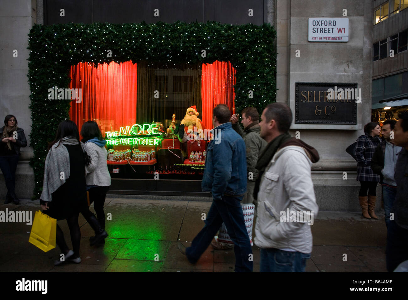 Weihnachts-Einkäufer gehen vorbei an Santa Claus in einem saisonalen Fenster des Kaufhauses Selfridges in der Oxford Street Stockfoto