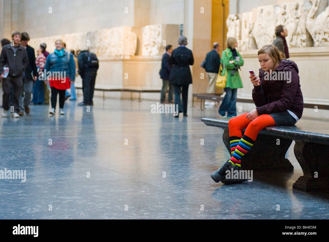 British Museum Innenraum junge Teenager Mädchen mit Handy rot Strumpfhose &  Bunte Socken Museum Galerie Sitzbank Stockfotografie - Alamy