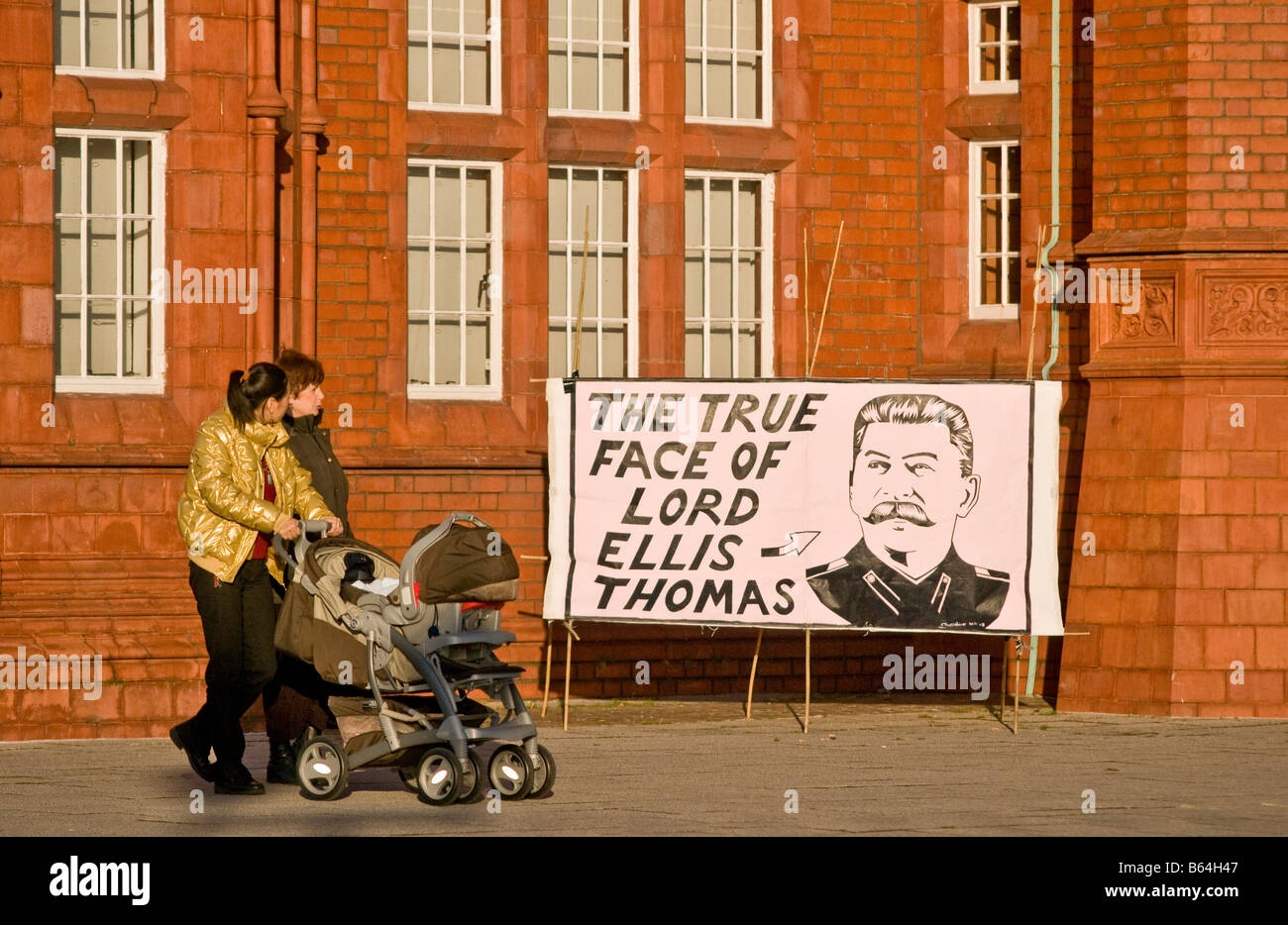 Zwei Frauen, ein Protest-Banner außerhalb der Pierhead Buolding Waliser Versammlung Regierung Cardiff Wales vorbeigehen Stockfoto