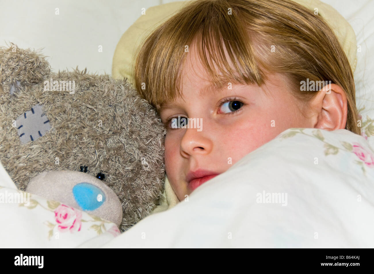 Ein junges Mädchen kuschelt im Bett mit ihren Teddybär. Stockfoto