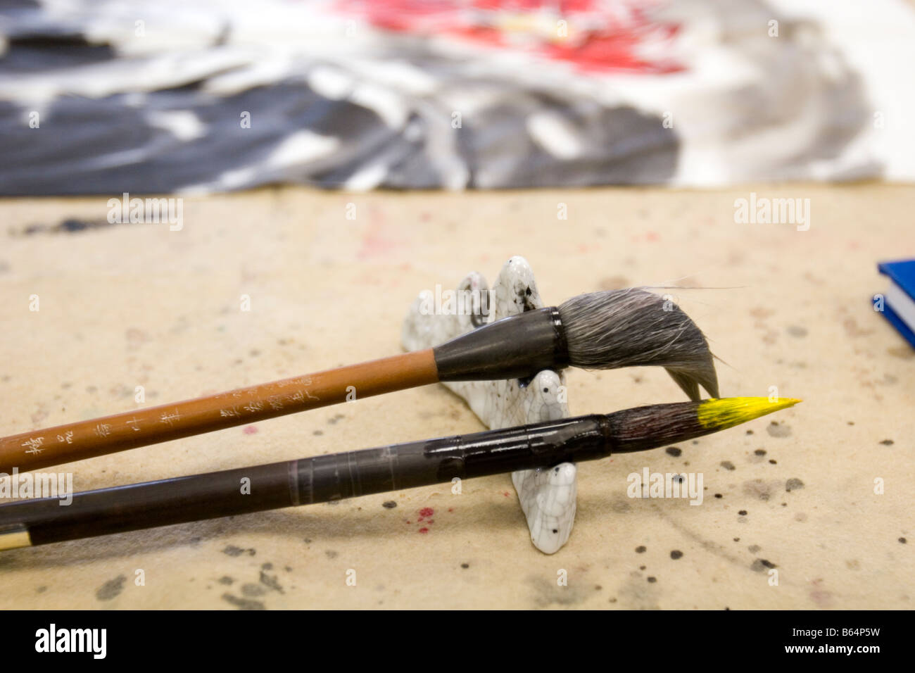 Zwei Künstler Pinsel auf einer Halterung sitzt in der Nähe von Gemälde des Künstlers. Stockfoto