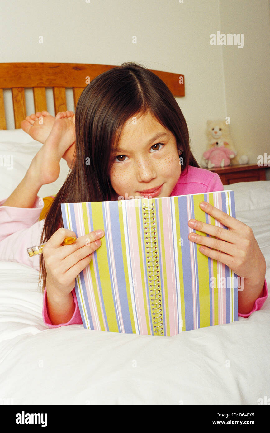 7 Jahre alten Mädchen schreiben Tagebuch auf ihrem Bett Stockfoto