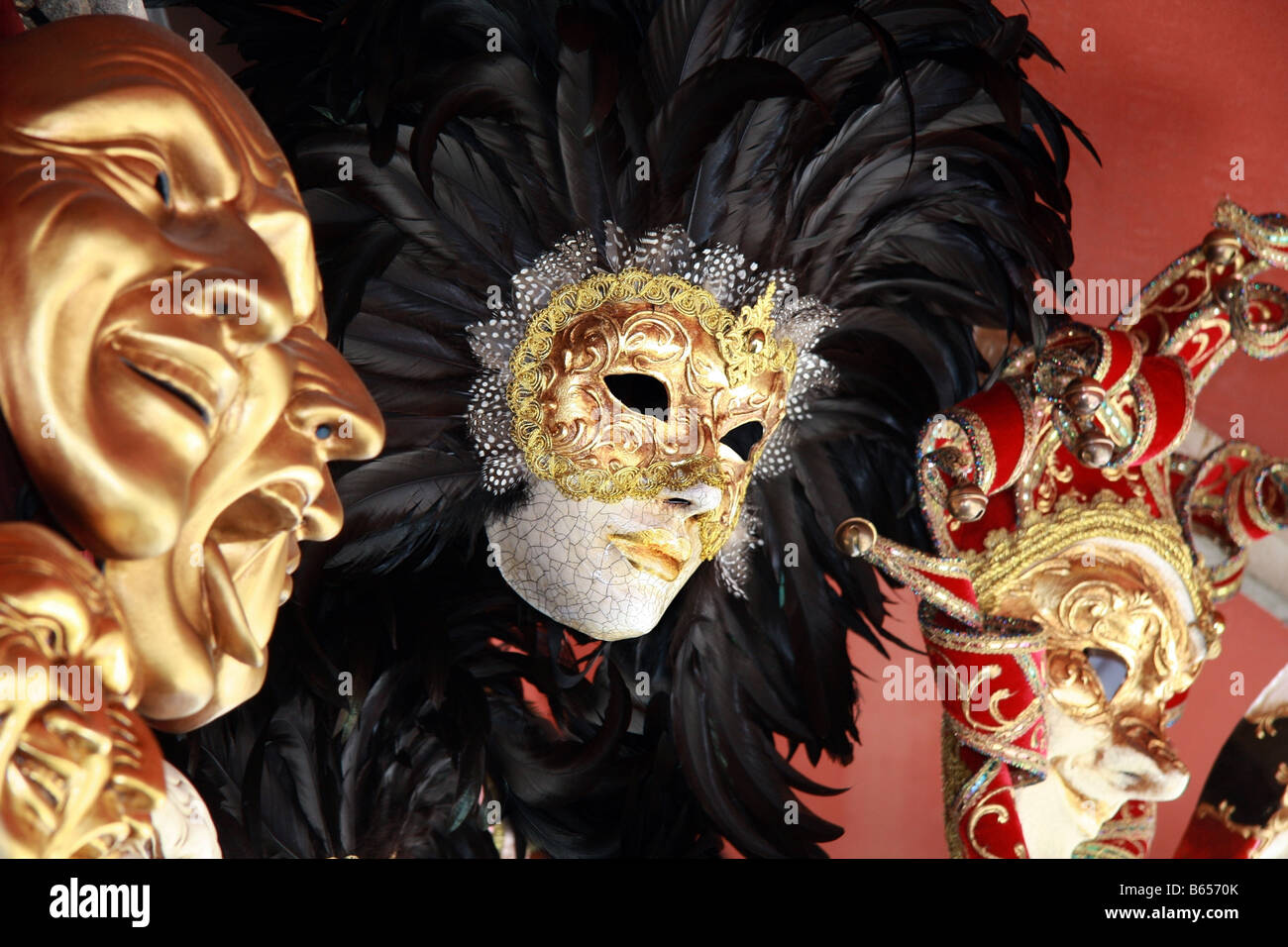 Venezianische Masken mit schwarzen Federn auf rotem Grund Stockfoto