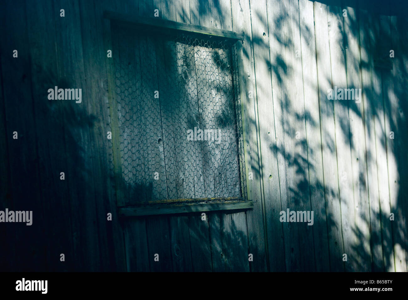 Holzwand, Fenster mit Brettern bedeckt mit Maschendraht Stockfoto