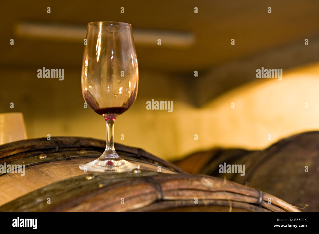 Leere Glas Wein gebeizt mit Rotwein auf Weinfass platziert Stockfoto