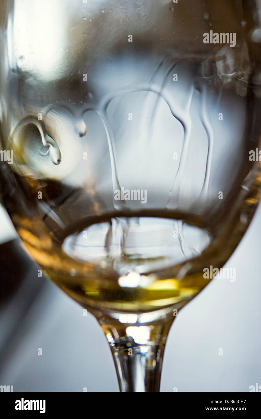Weißer Wein tropft nach unten innerhalb des Weinglases, extreme Nahaufnahme Stockfoto