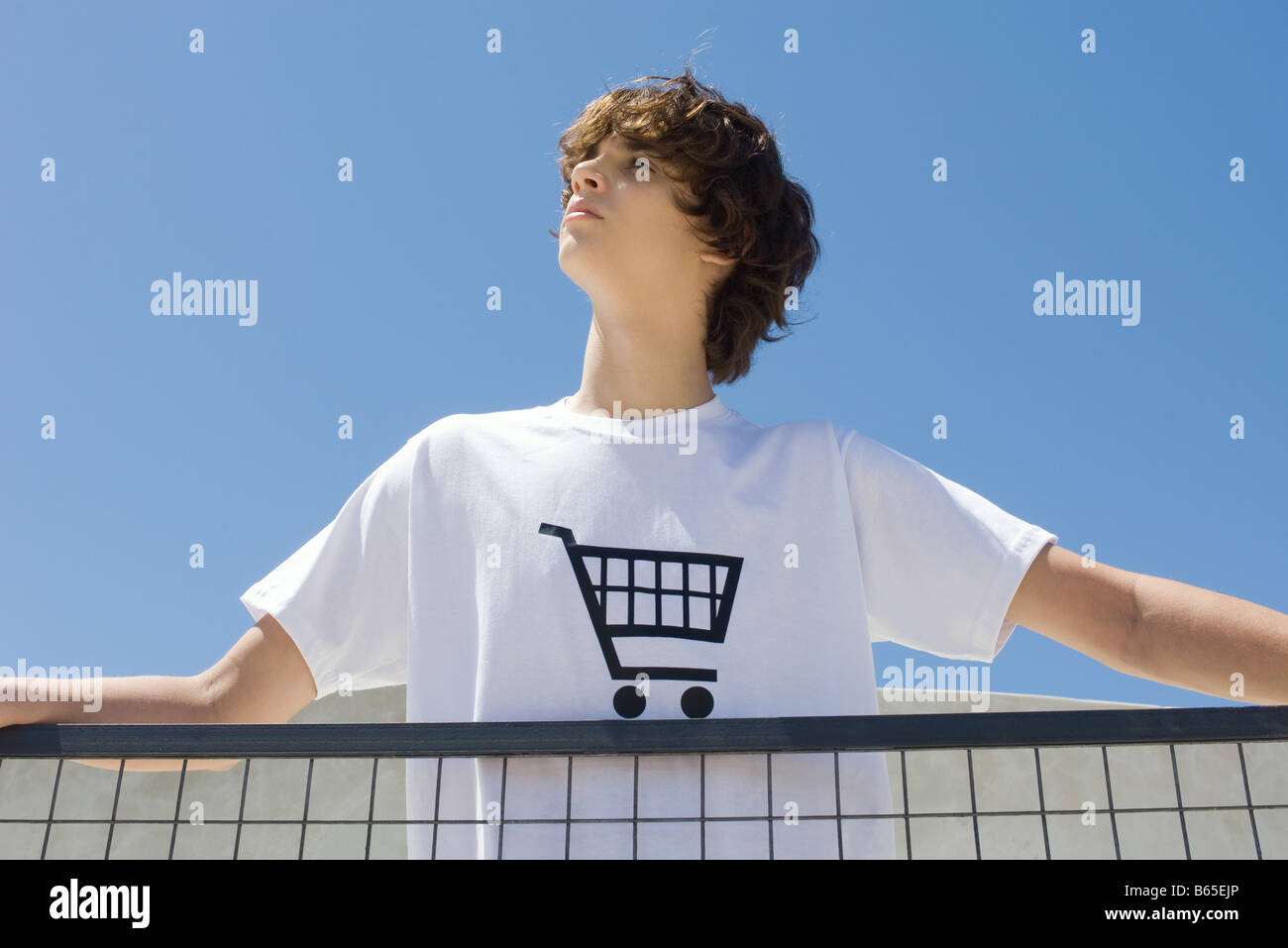 Teenager tragen t-Shirt bedruckt mit Einkaufswagen, stehend am Geländer, nachschlagen Stockfoto