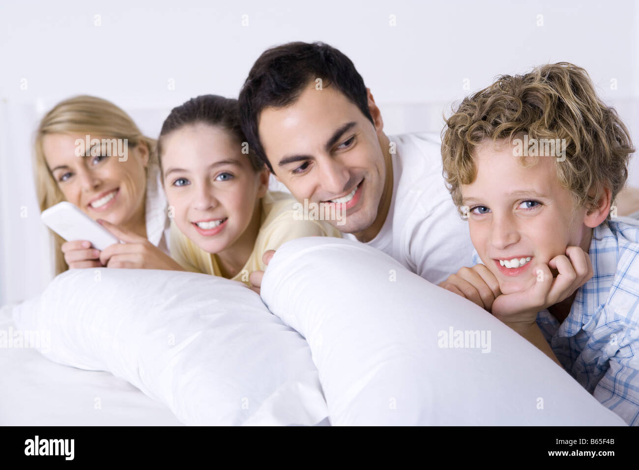 Familie gemütlich im Bett zusammen, Vater auf der Suche nach Sohn lächelnd in die Kamera, Stockfoto