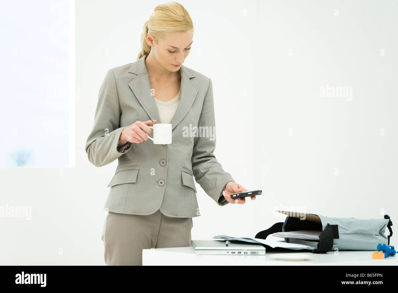 Berufstätige Frau mit Kaffeetasse, blickte, SMS-Nachrichten Stockfoto