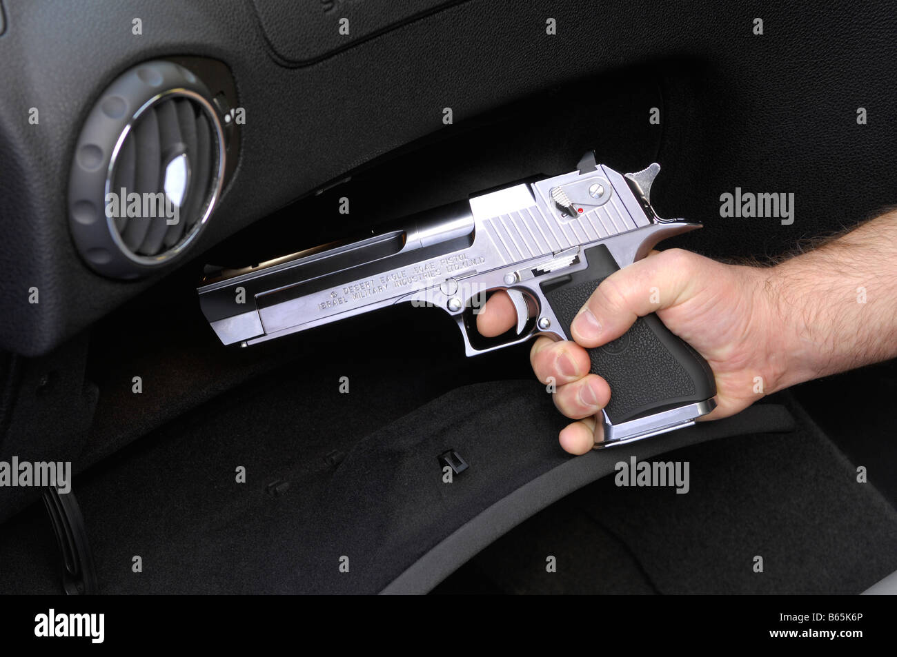 Replikat automatische Pistole gezogen von Handschuhfach des Autos Stockfoto