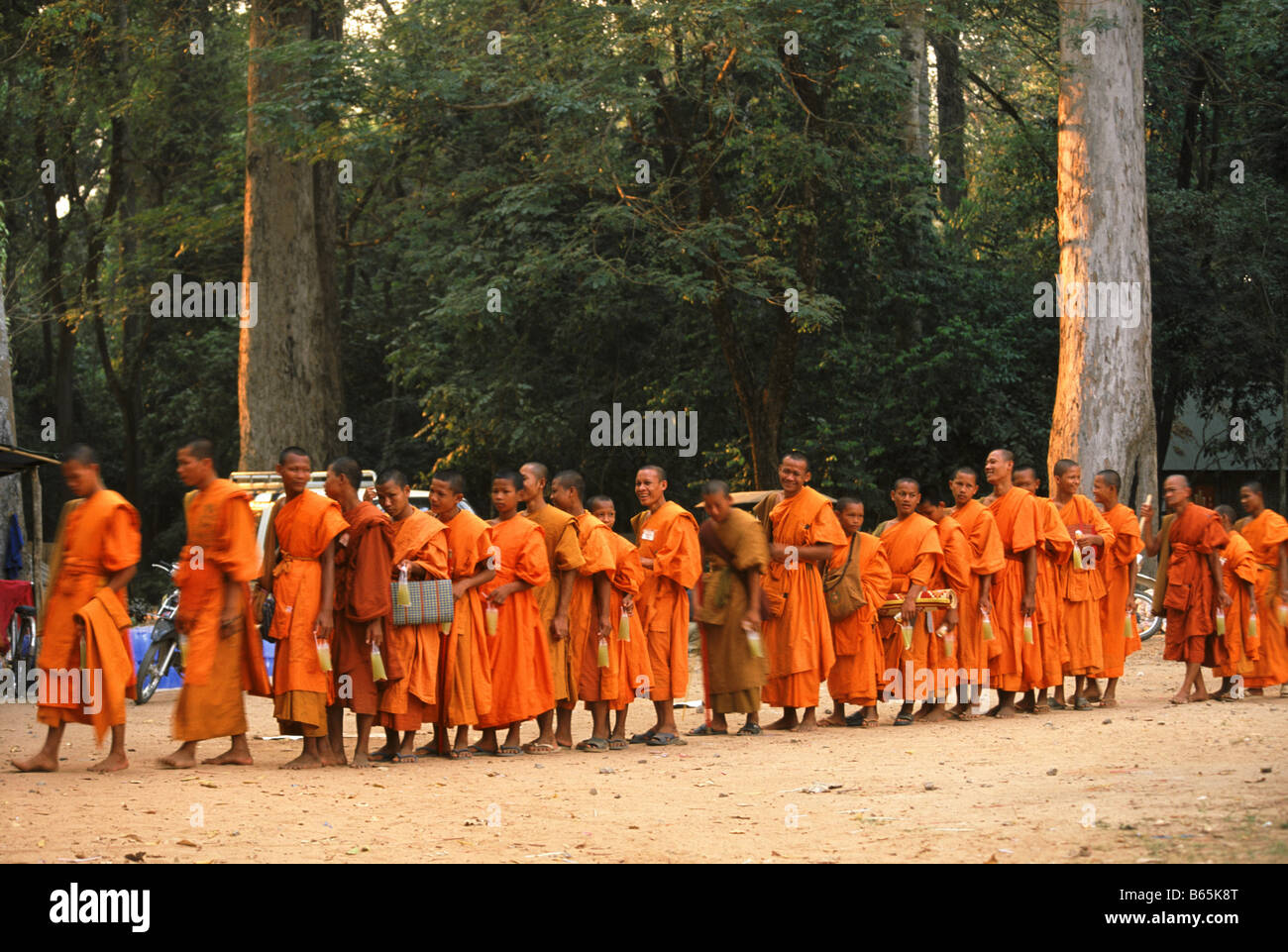 LINIE DER MÖNCHE, DIE DARAUF WARTEN, AUF DER GEGENÜBERLIEGENDEN TEMPEL BAYON, ANGKOR WAT KOMPLEX, SIEM REAP, KAMBODSCHA RESPEKTIEREN. Stockfoto