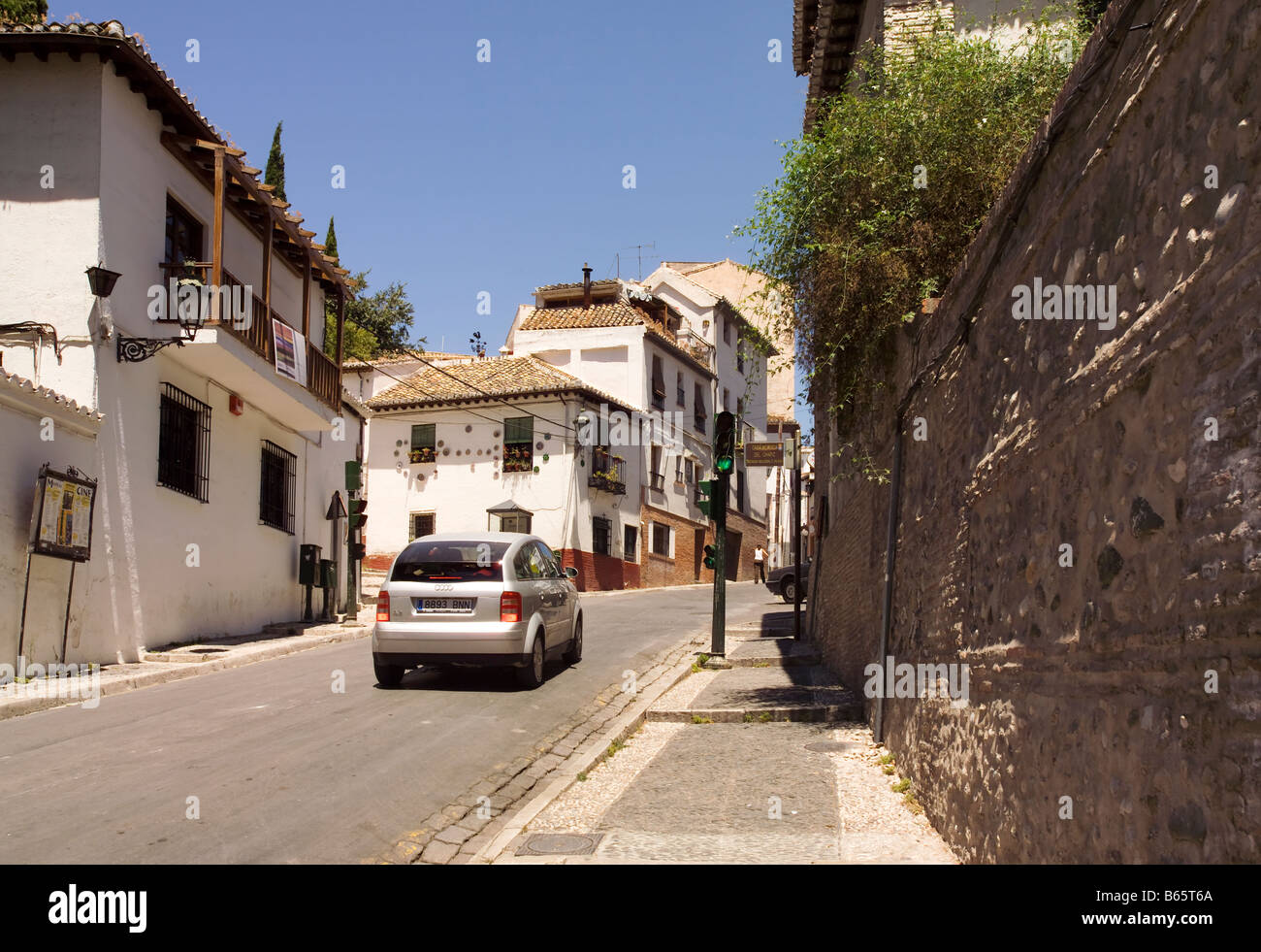 Eine Straße mit weiß gewaschen gestrichenen Häusern. Ein Auto Audi A2 vorbei an Ampeln Granada, Andalusien, Spanien, Europa. Stockfoto