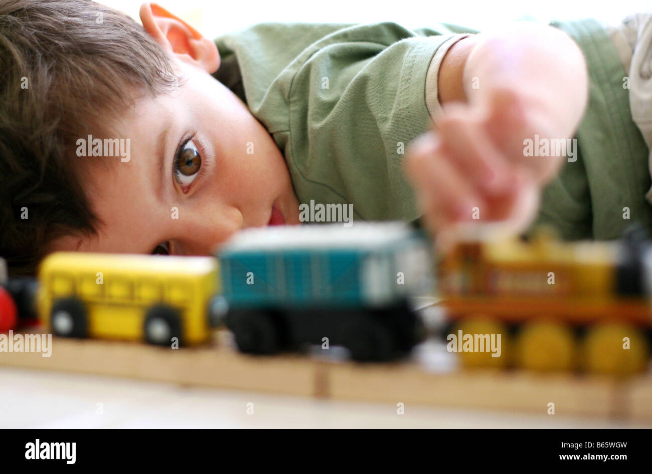 Ein Junge spielt mit einem hölzernes Spielzeug-Eisenbahn-set Stockfoto