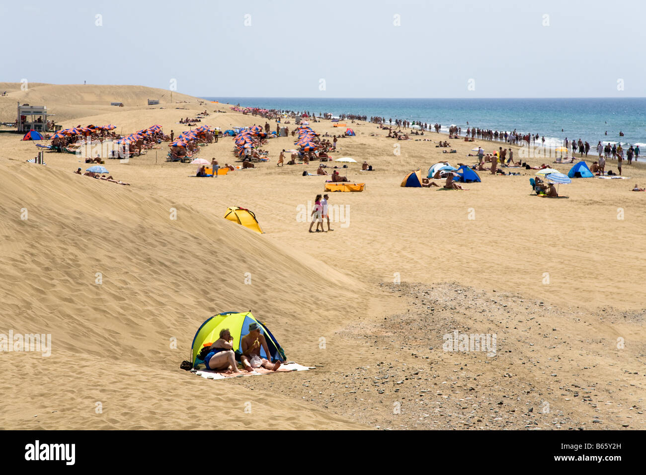 Massen von Menschen, die zum Sonnenbaden am Strand von Maspalomas Gran Canaria Spanien Stockfoto