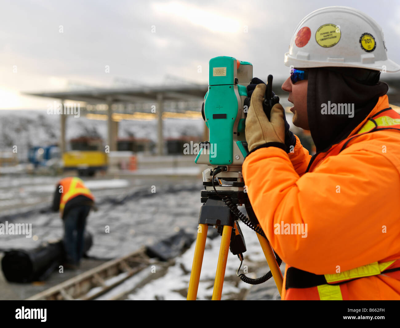 Baustelle im Winter mit Vermessungsingenieur, die eine Lesung auf einem digitalen Transit Theodolit Stockfoto