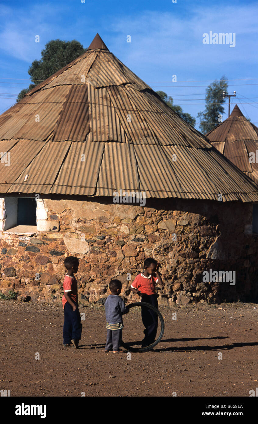 Eritreische Jungs spielen mit einem Reifen oder mit dem Fahrrad Reifen außerhalb des runden Haus oder Hütte, Asmara, Eritrea Stockfoto